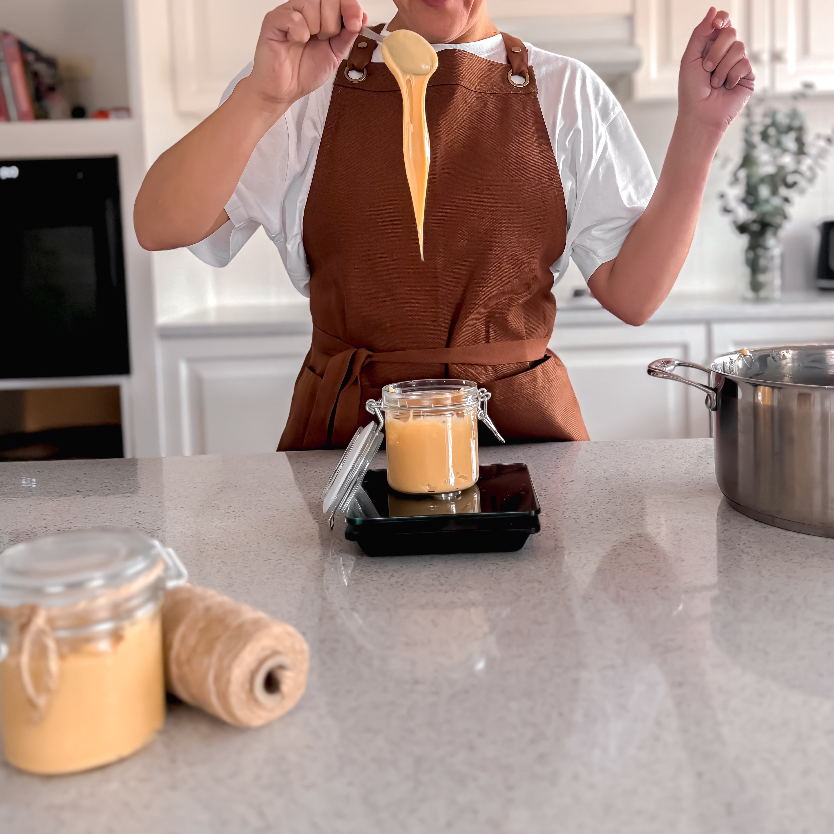 Silvia, a self-taught Peruvian baker in Melbourne, standing in her kitchen holding a jar of homemade manjar blanco/dulce de leche.