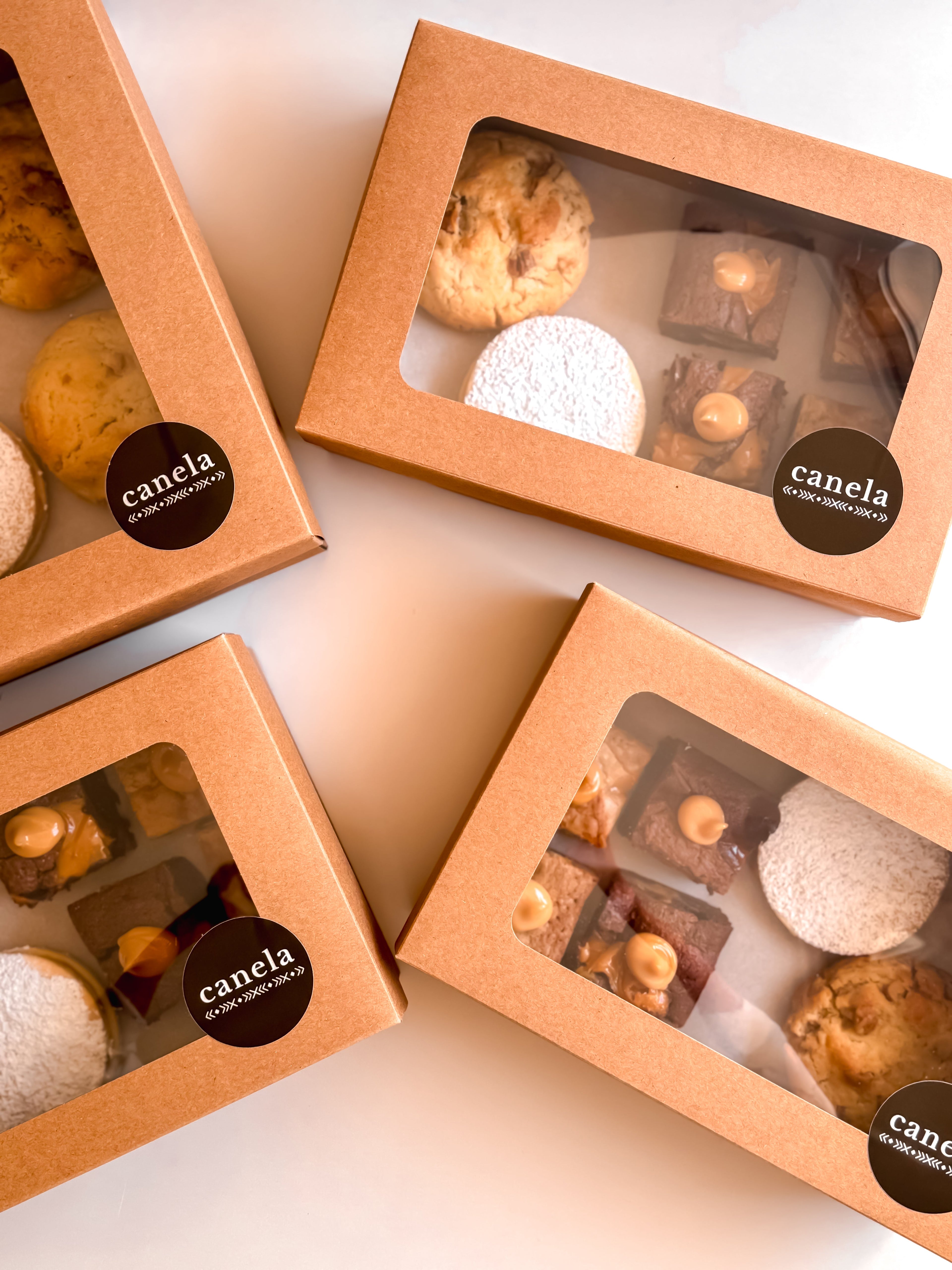 Assorted Canela dessert boxes in kraft packaging, each with a mix of alfajores, brownies, and blondies - ideal for gifting or sharing at gatherings.