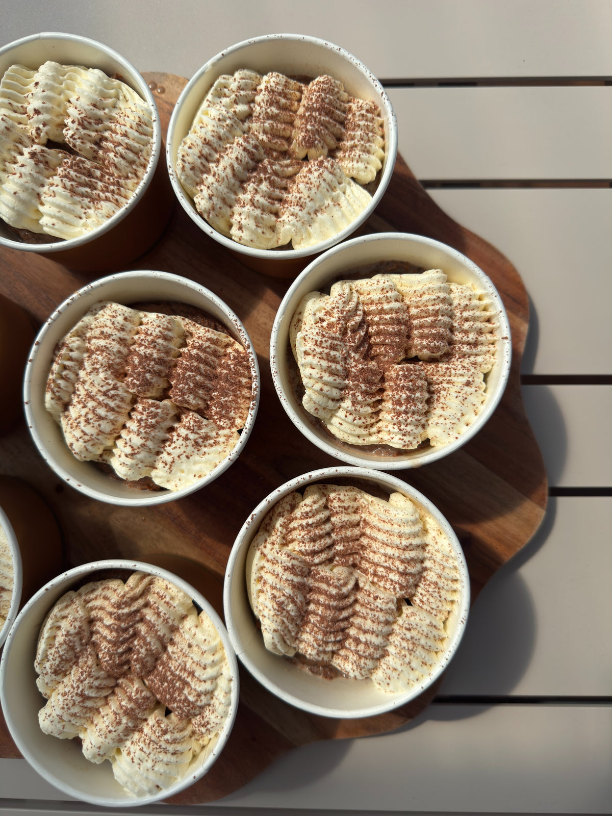 Mocha tres leches dessert cups topped with piped whipped cream and a dusting of cacao.
