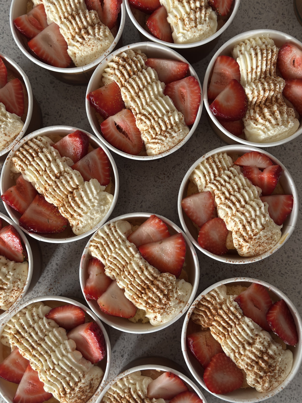 Individual strawberry tres leches dessert cups topped with whipped cream and fresh strawberries.